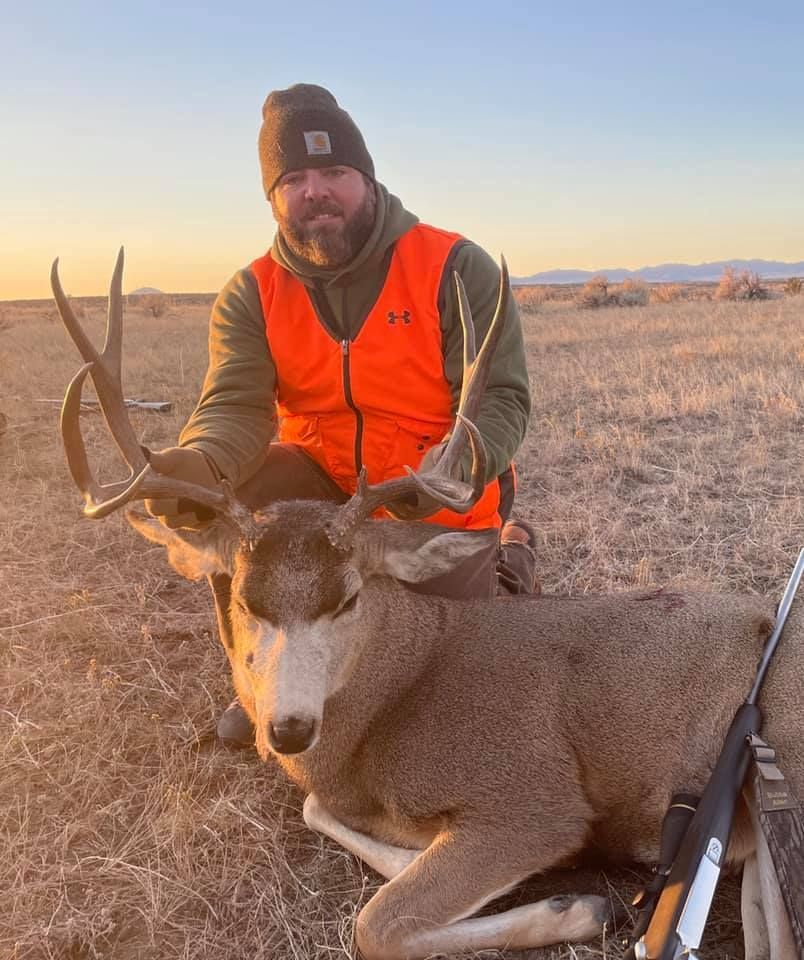 Man posing with deer in a forest