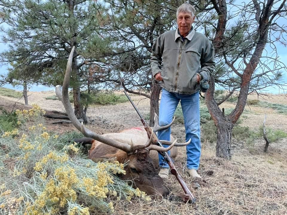 Man posing with deer in a forest