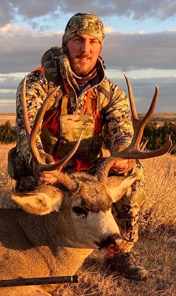 Man posing with deer in a forest