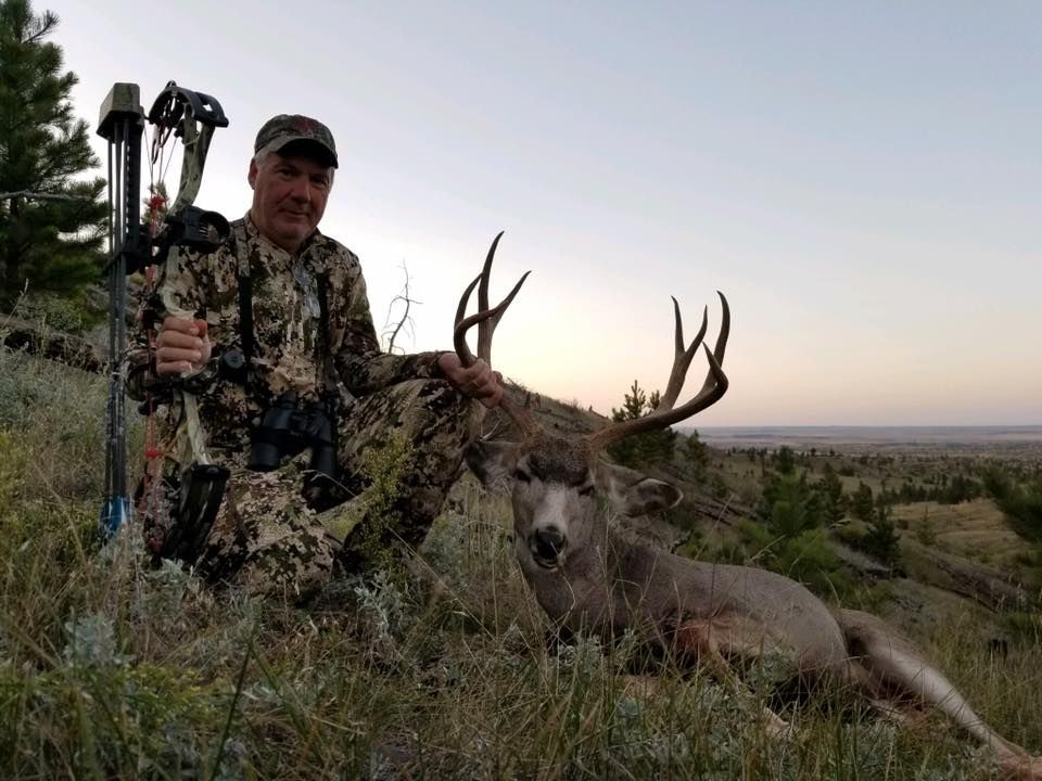 Man posing with deer in a forest
