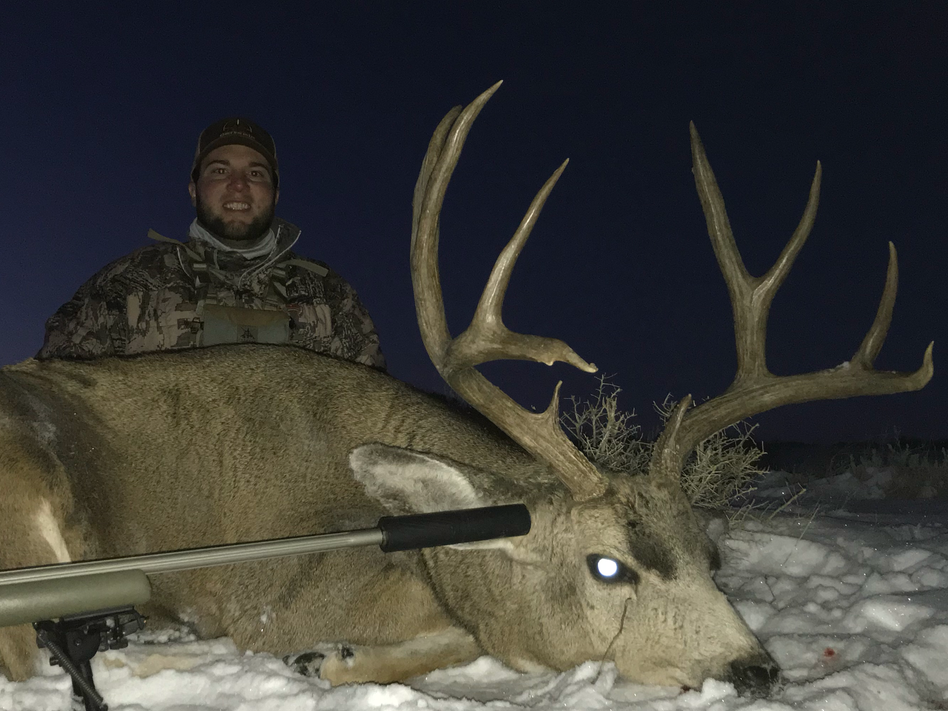 Man posing with deer in a forest