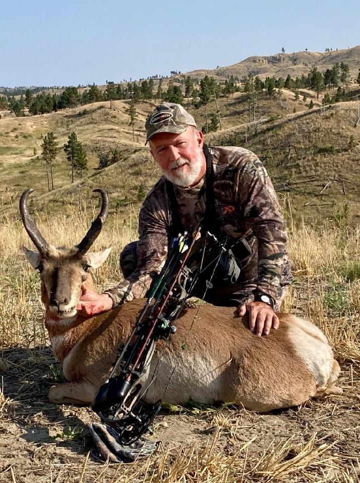 Man posing with deer in a forest