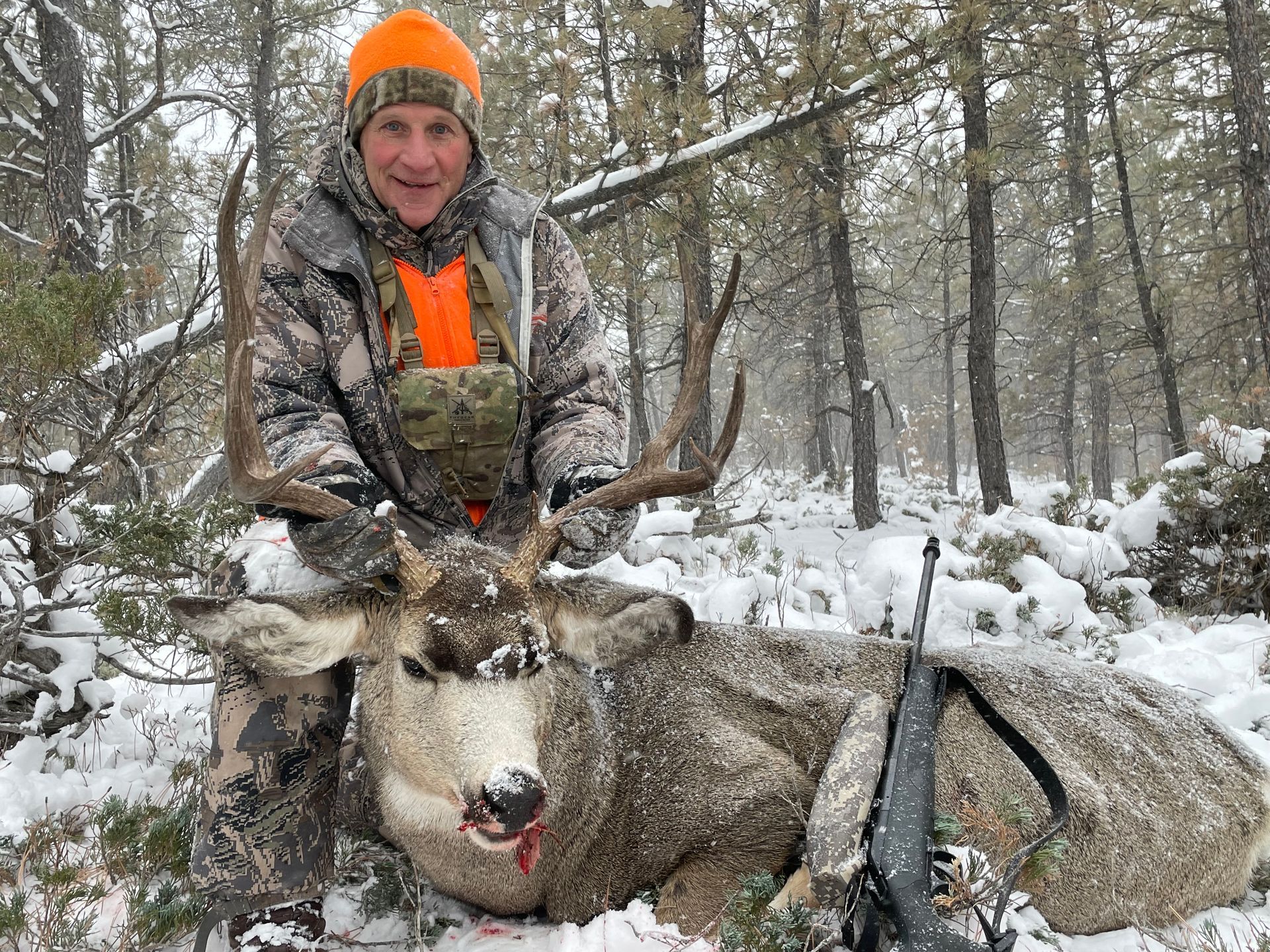 Man posing with deer in a forest