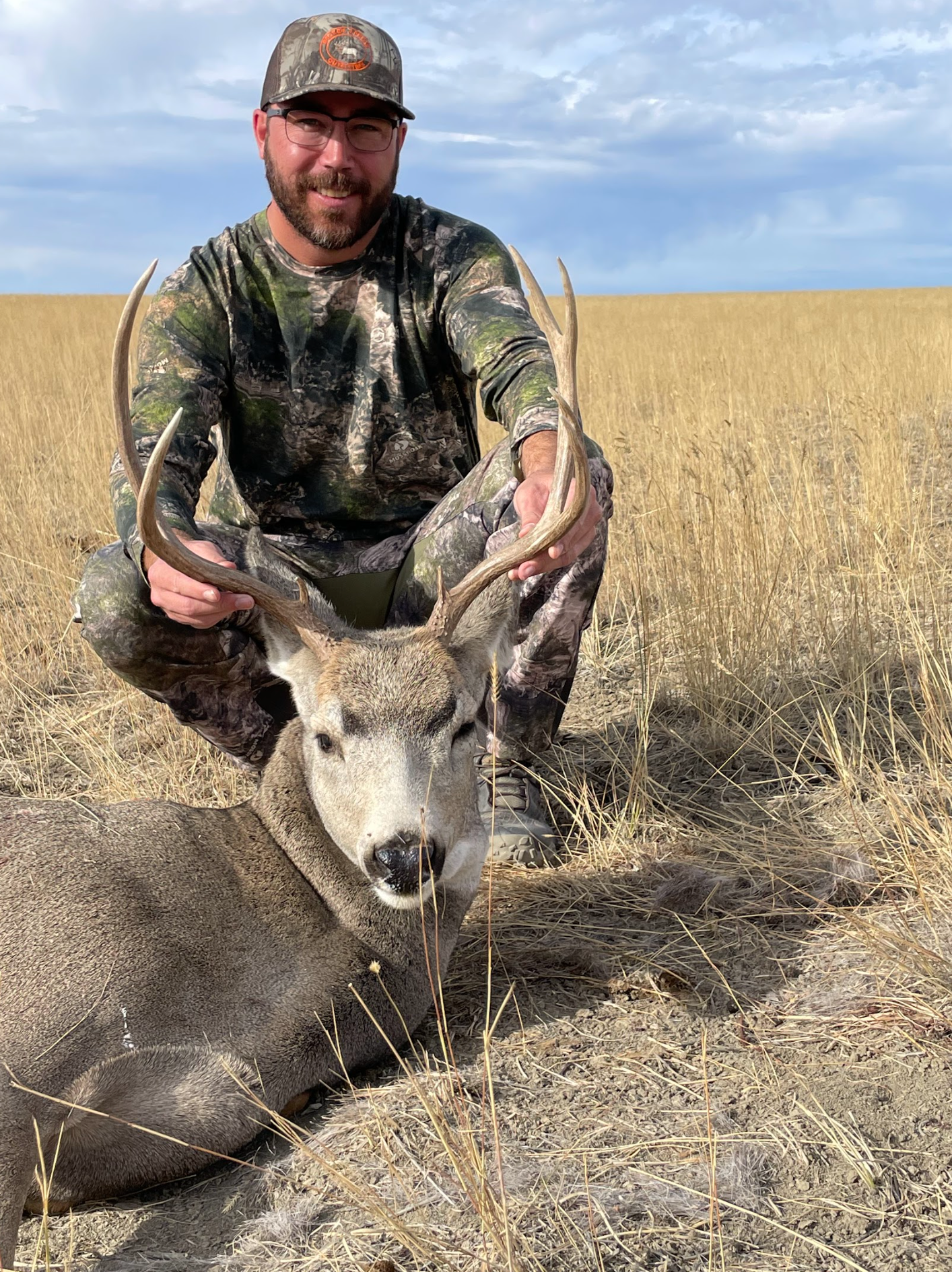 Man posing with deer in a forest