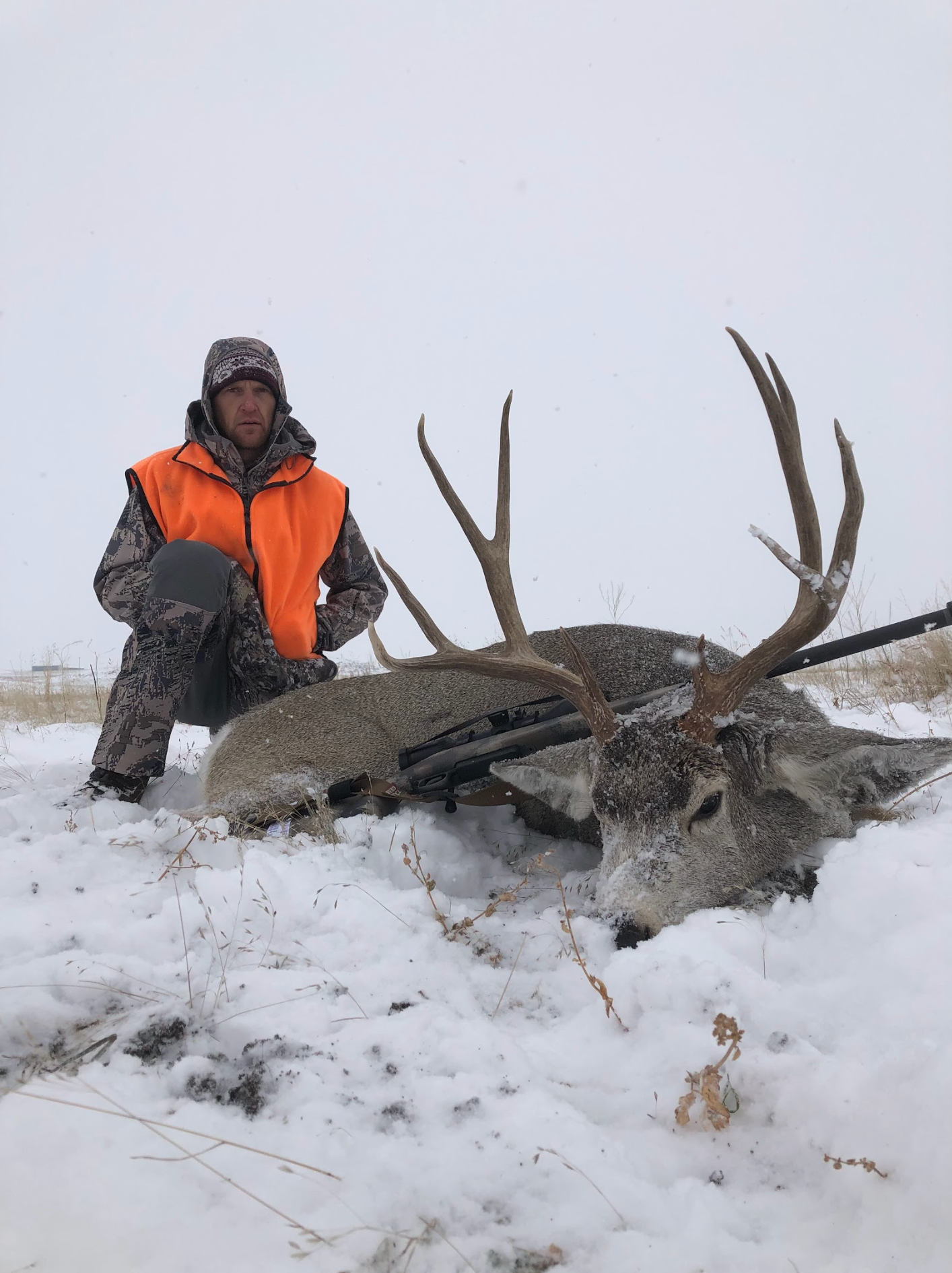 Man posing with deer in a forest