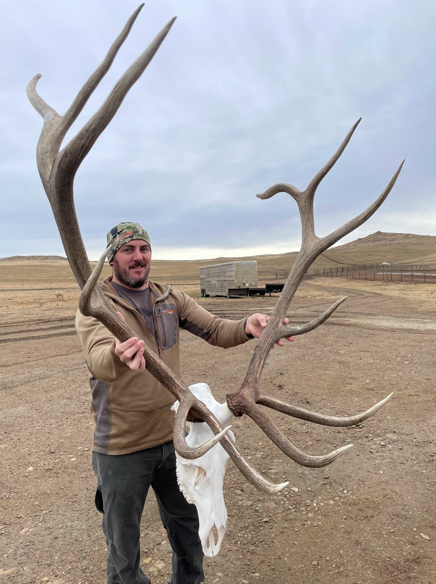 A man is holding a large deer antlers and a deer skull.