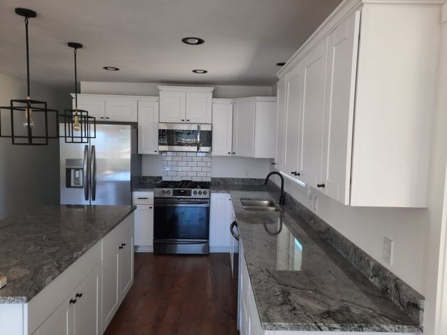 White kitchen with granite countertops, stainless steel appliances, and black accents.