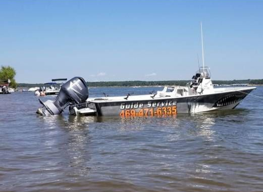 A white motorboat sits partially submerged in calm water with a clear blue sky in the background.