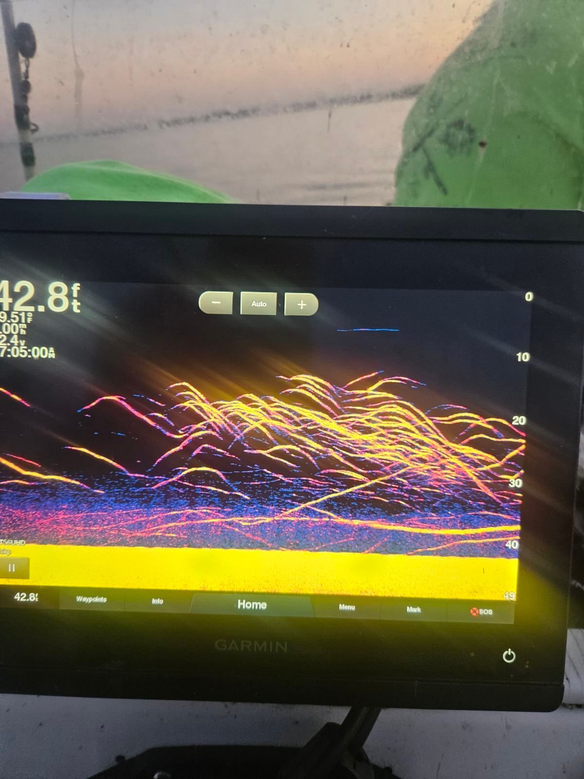 Garmin fish finder screen displaying a large school of fish underwater with yellow, orange, and blue sonar echoes.