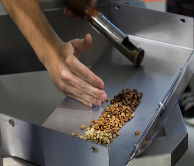 Hand Putting Coffee On A Metal — Woodbridge, VA — Happy Place Coffee & Eats