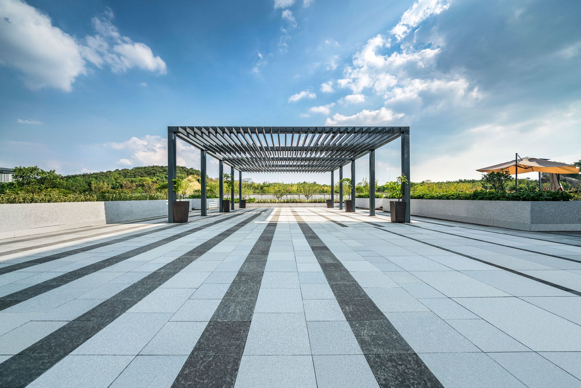 An empty parking lot with a pergola and a blue sky in the background.