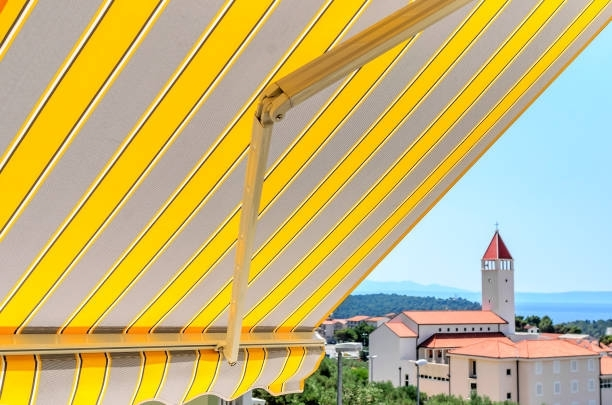 A yellow and white striped awning with a church in the background