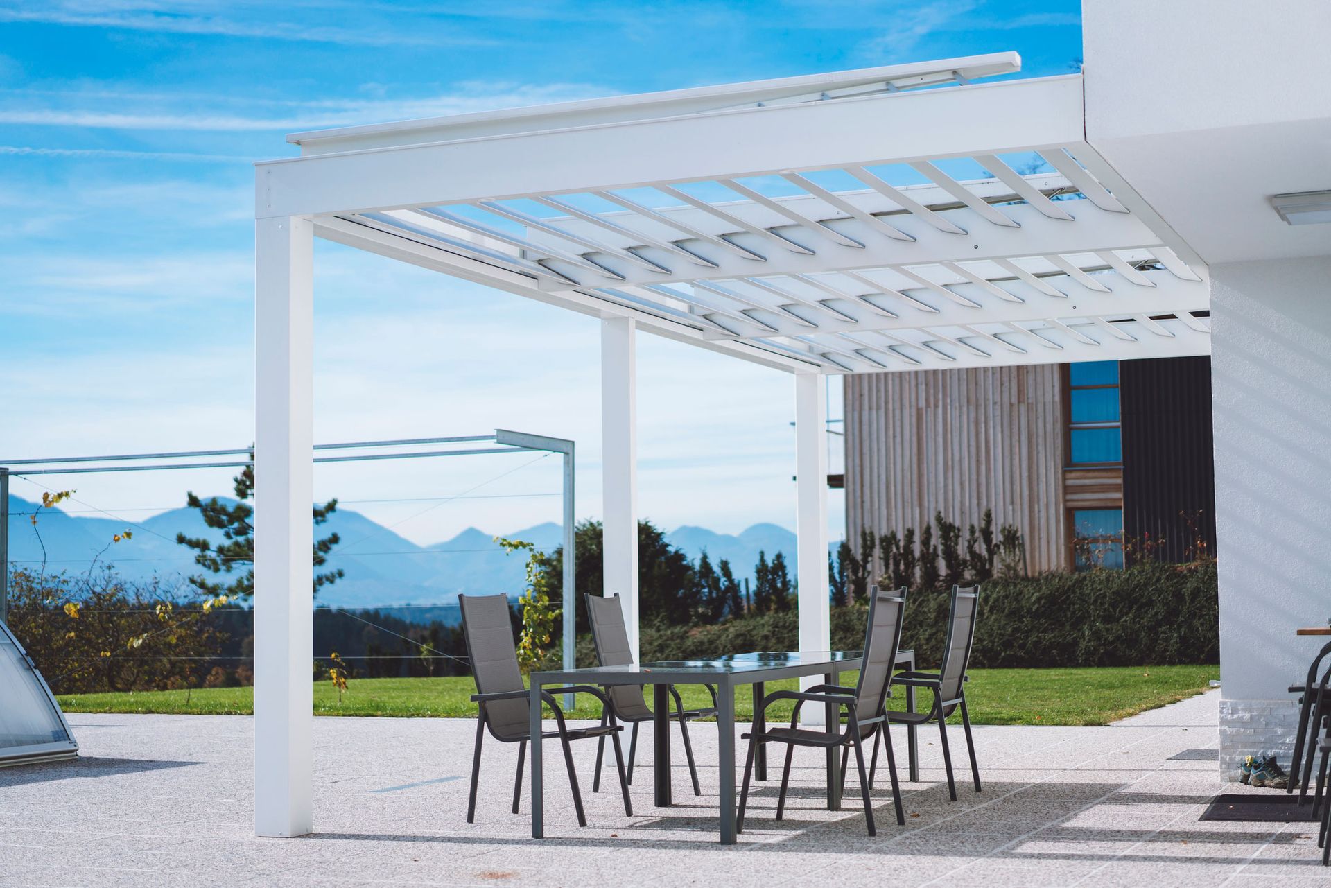 A white pergola with a table and chairs underneath it