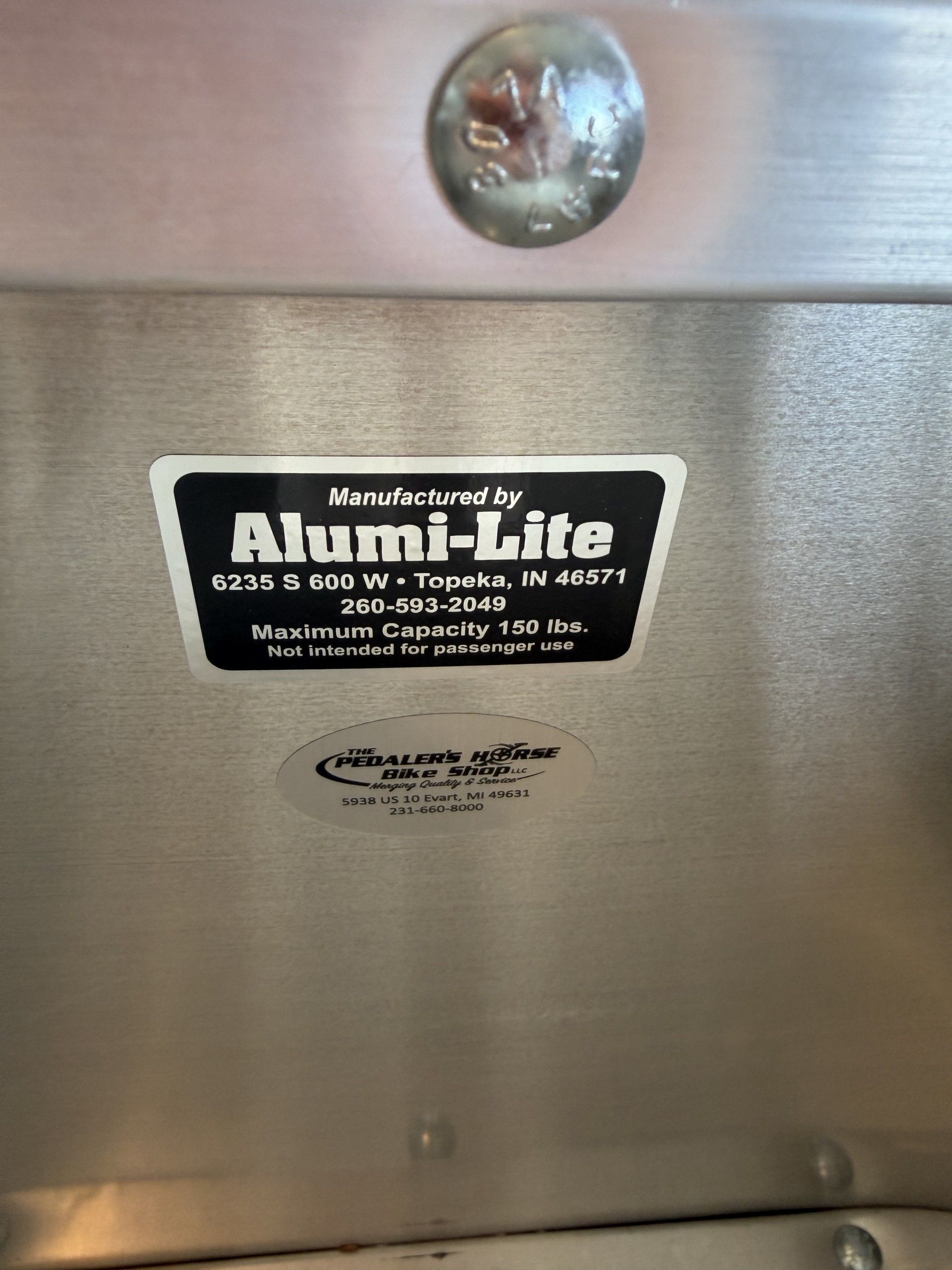 Metal surface with an Alumi-Lite manufacturer label listing the company address, phone number, and a 500-pound limit.