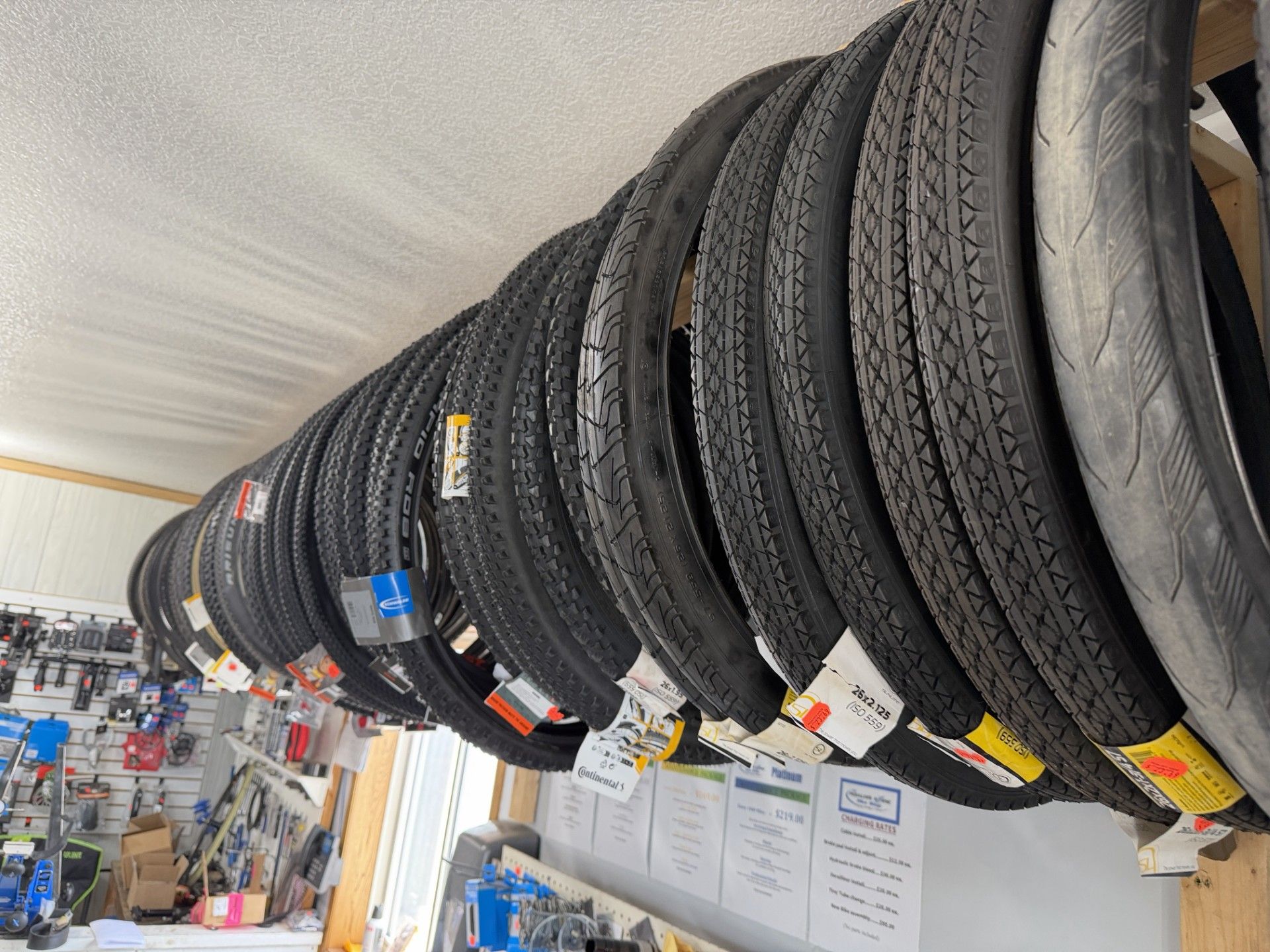 A row of new motorcycle tires hanging on a wooden rack inside a shop.