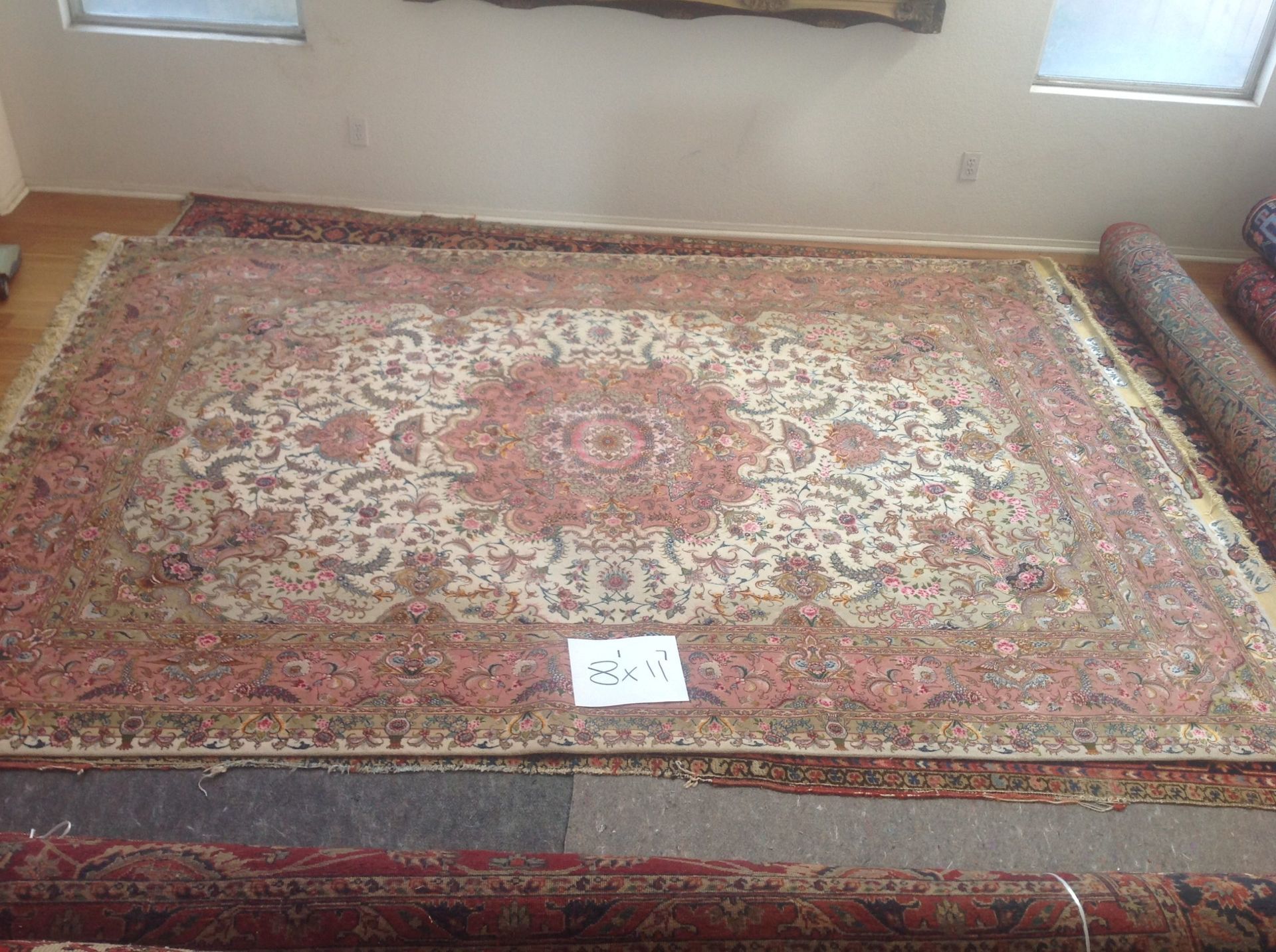 A large rug is sitting on top of a wooden floor in a living room.