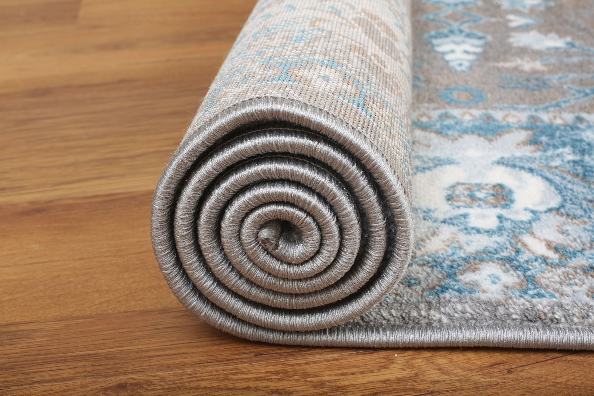 A rug is rolled up on a wooden floor.