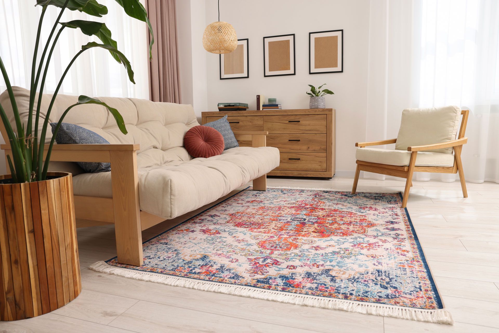 A living room with a couch , chair , rug and potted plant.