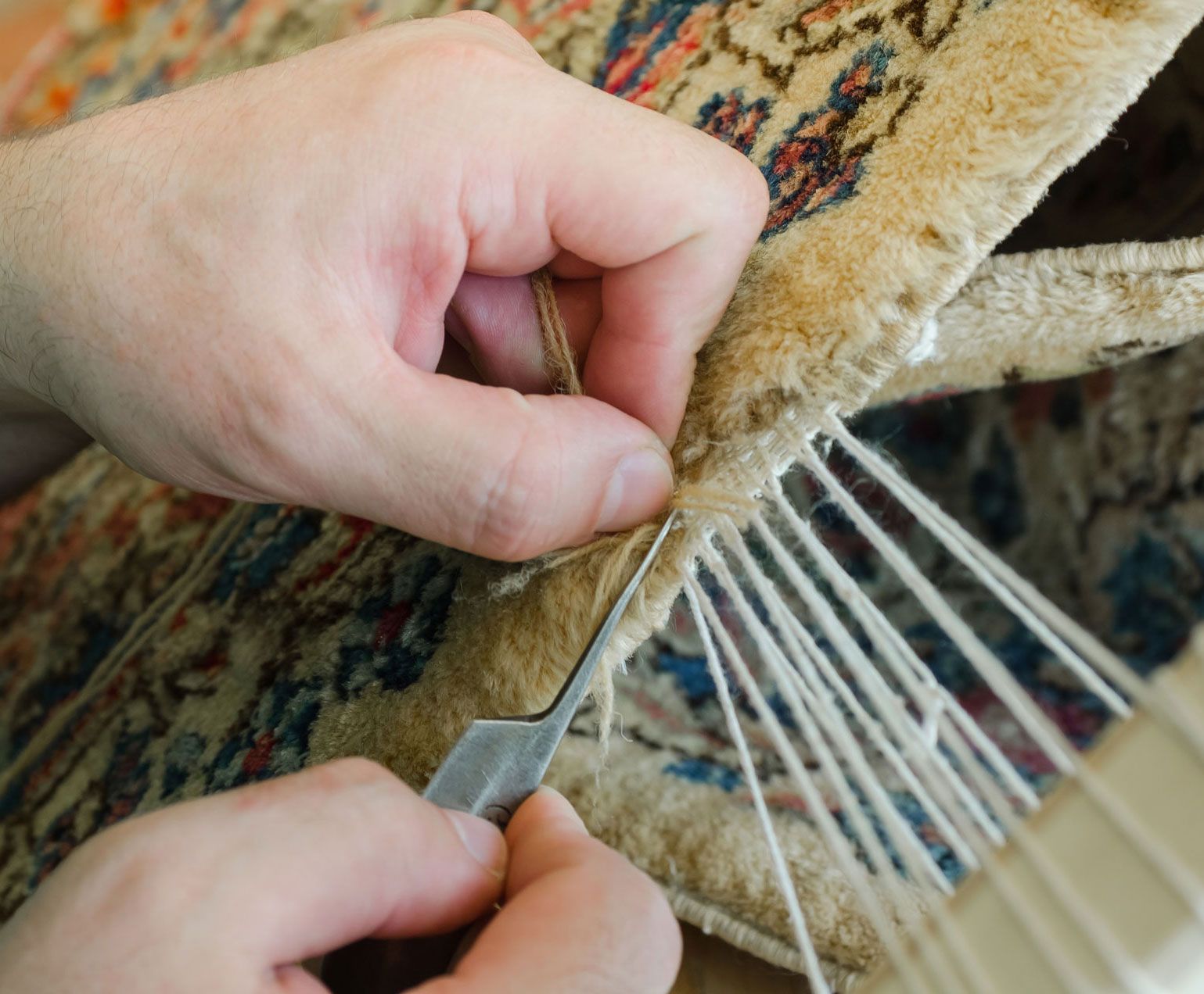 A person is working on a rug with tweezers