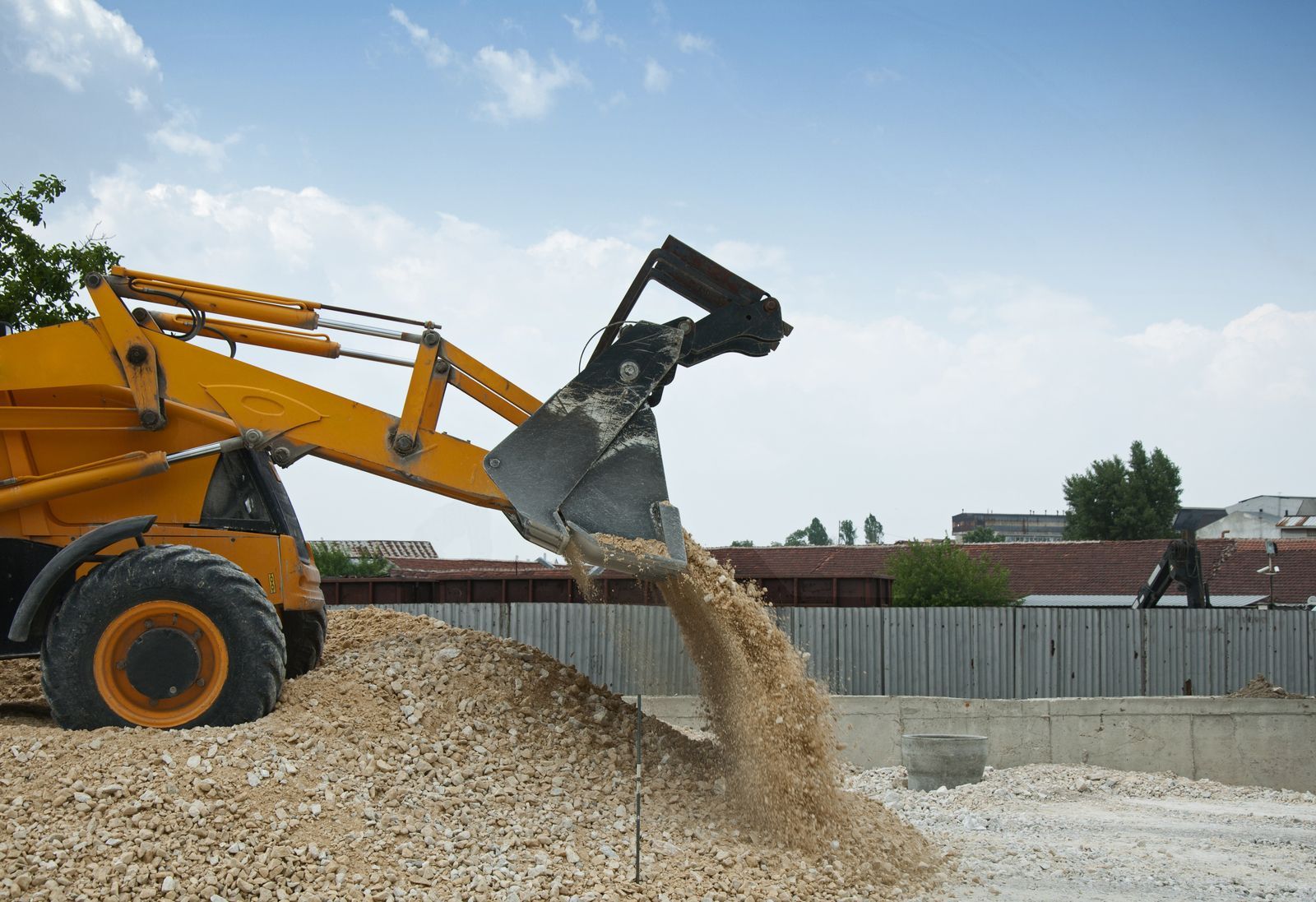 a yellow construction vehicle is dumping gravel into a pile