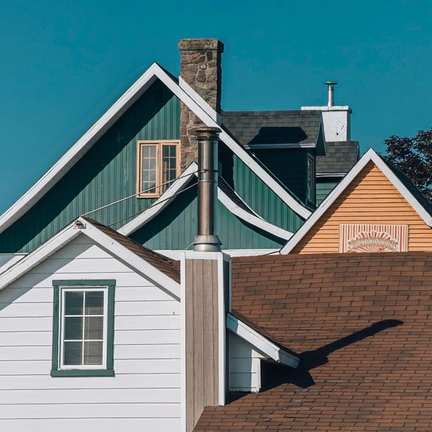 A green and white house with a chimney on the roof