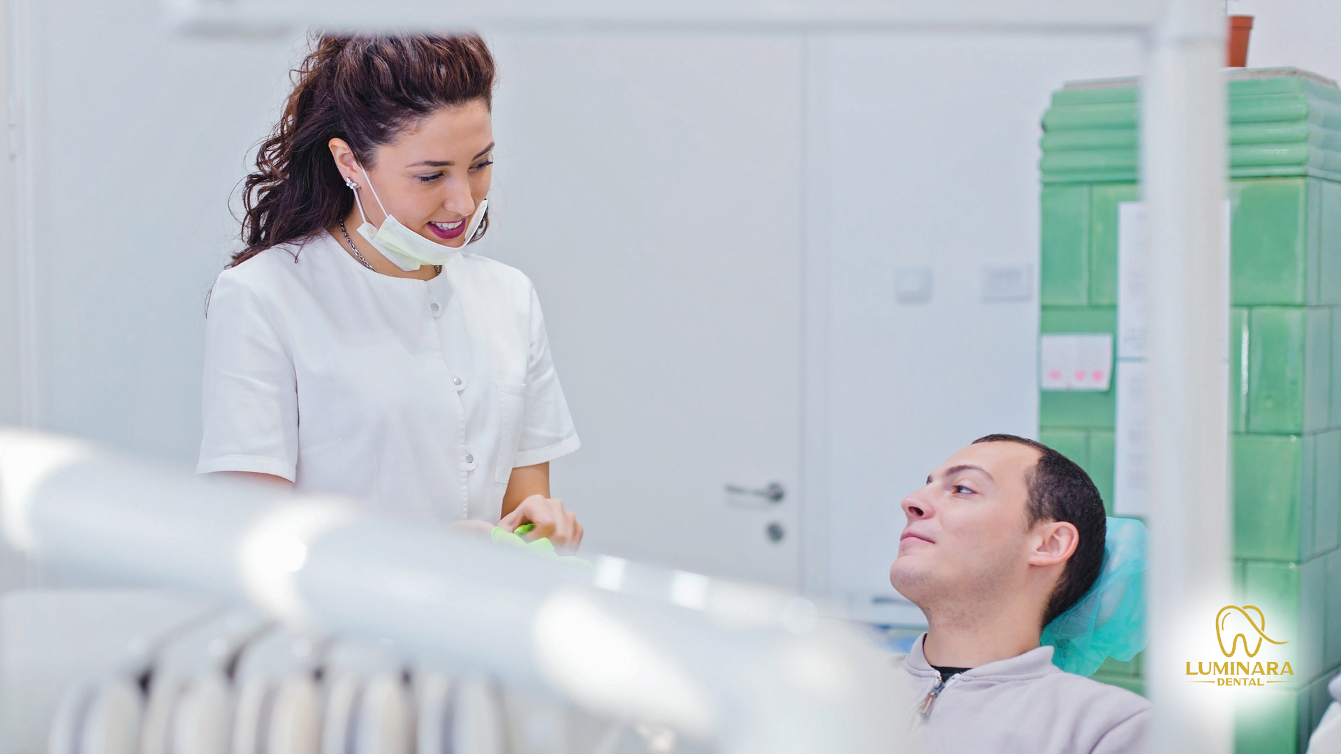 A dentist is talking to a patient in a dental chair.