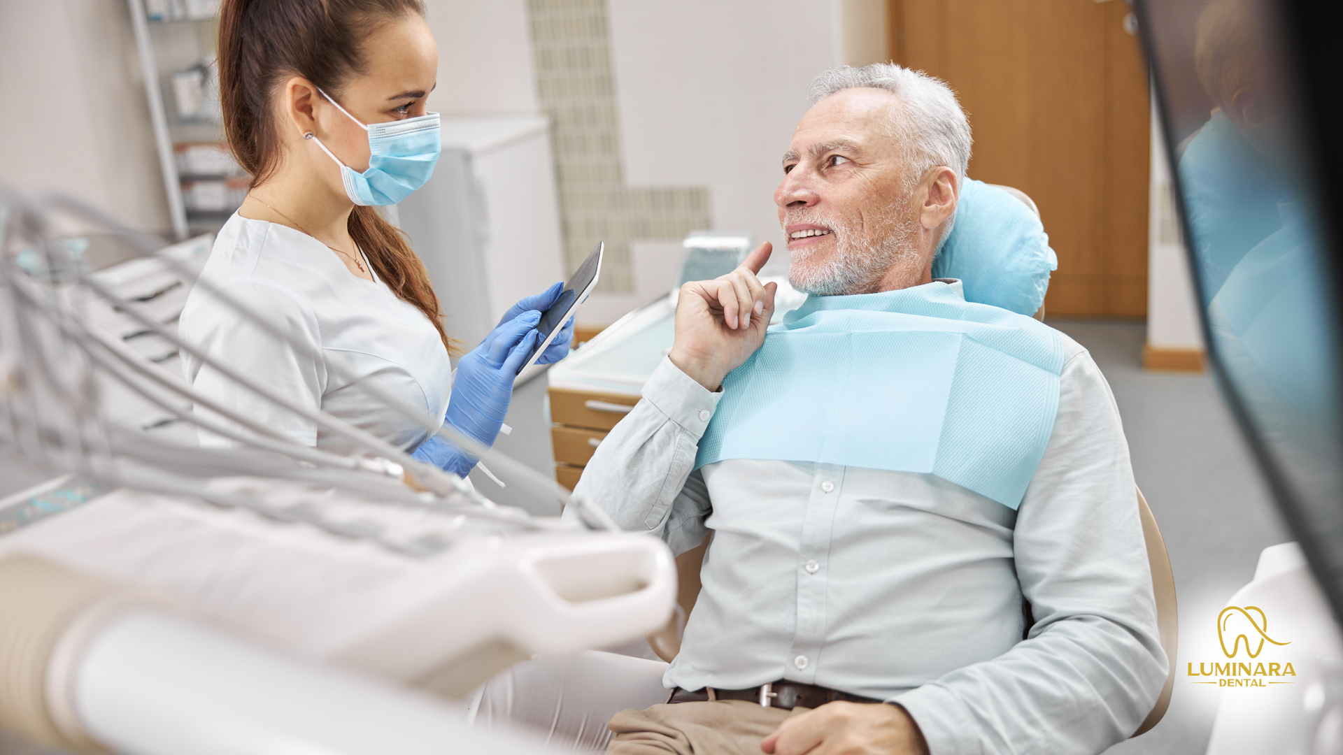 Dentist in mask and gloves examining a patient seated in a dental chair.