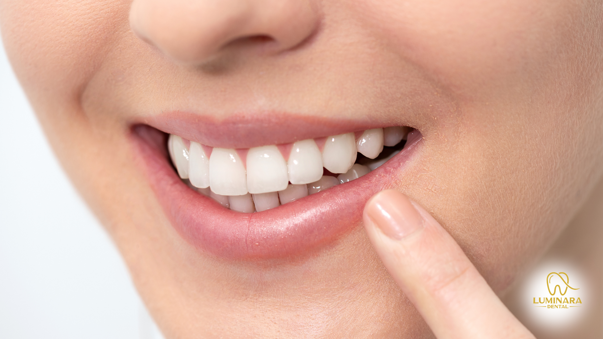 Close-up of a person's smiling mouth, pointing at their bright, white teeth.