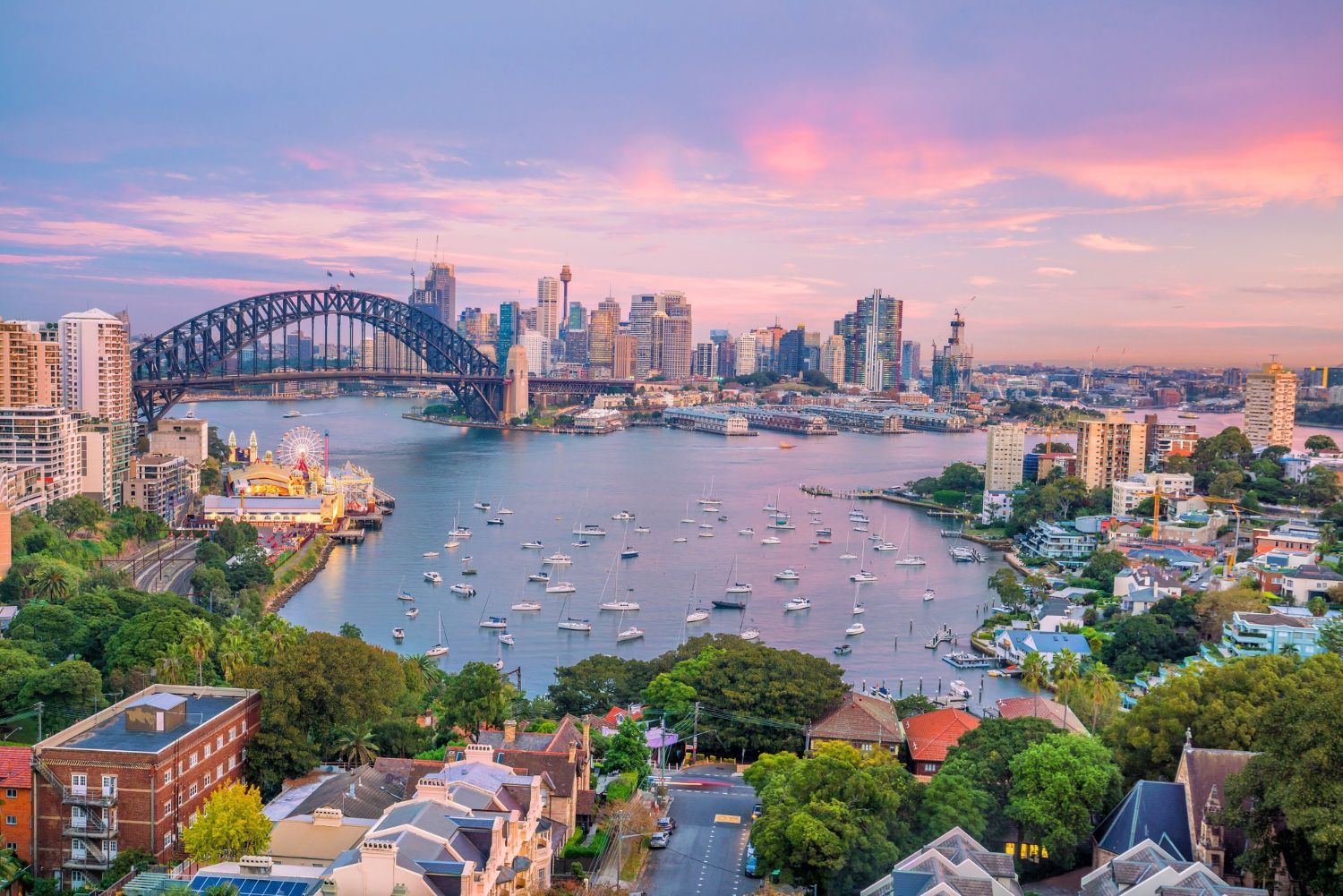 An aerial view of sydney harbor and the city skyline at sunset.