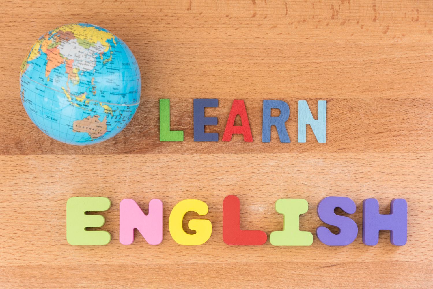 A globe is on a wooden table next to the words learn english