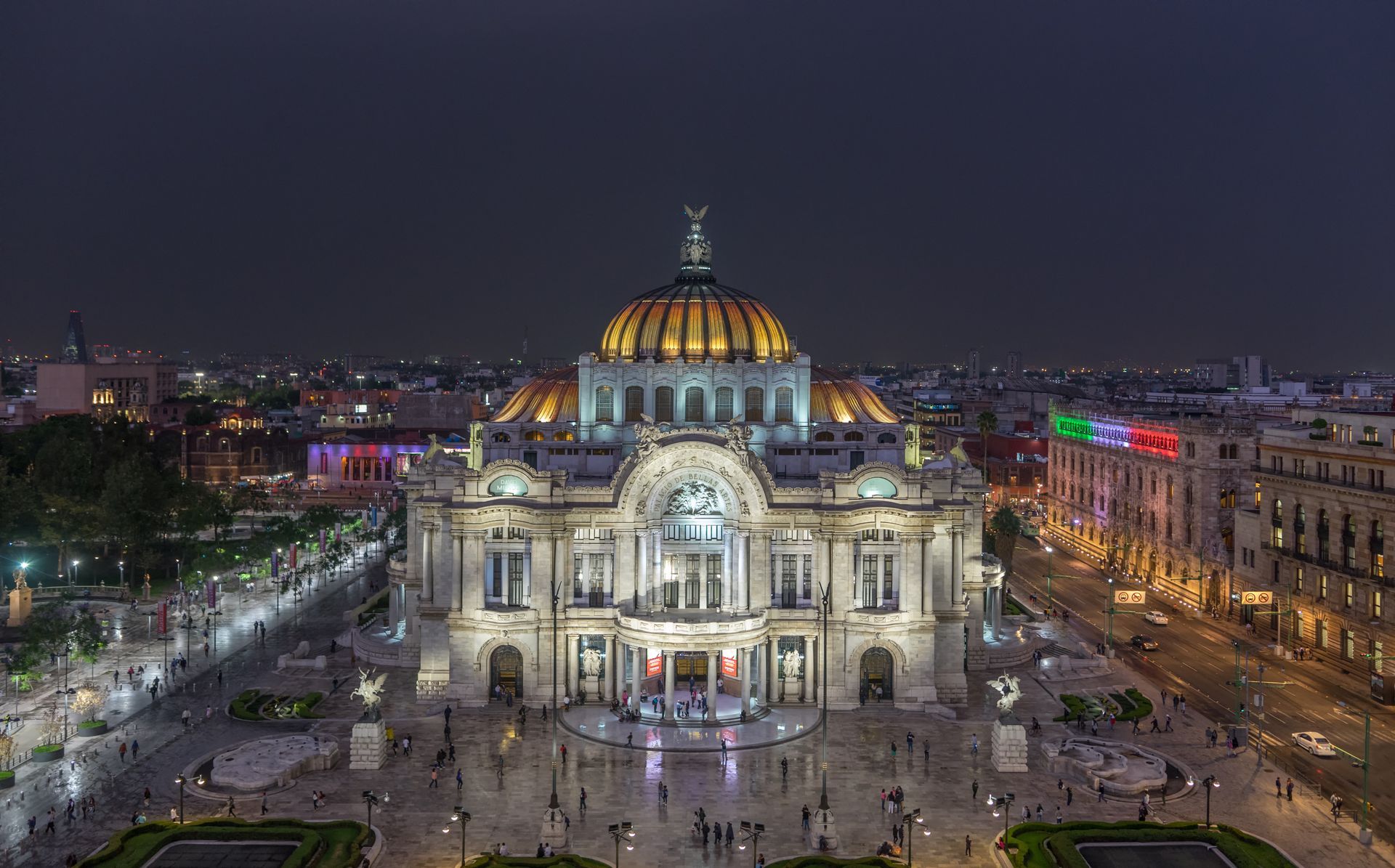 A large building with a dome on top of it is lit up at night.