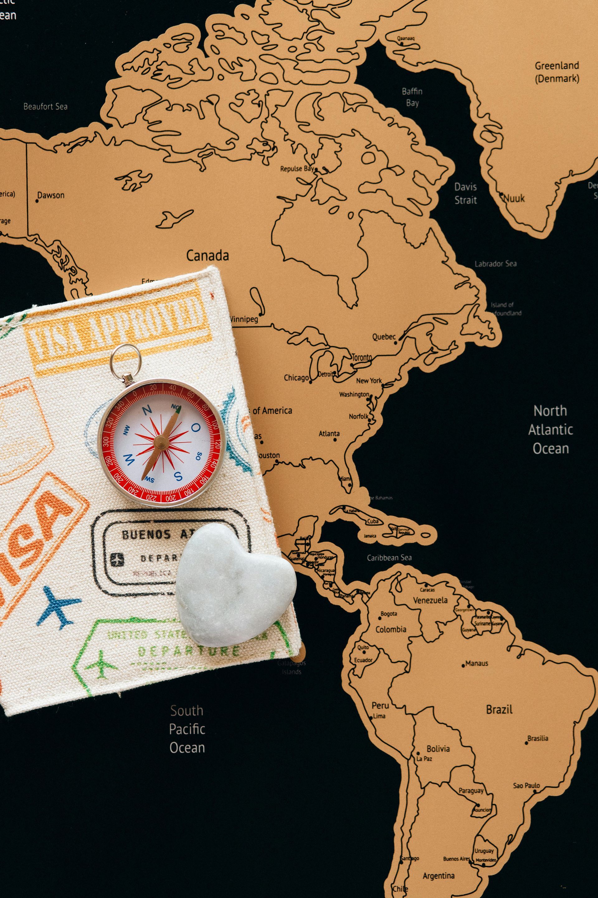 A compass is sitting on top of a map next to a passport.
