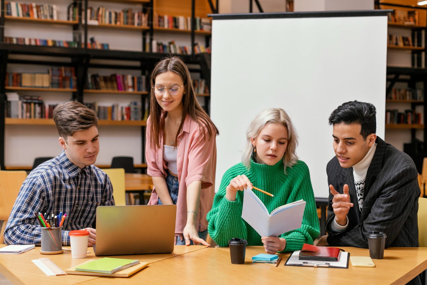 A group of young people are sitting at a table in a library.