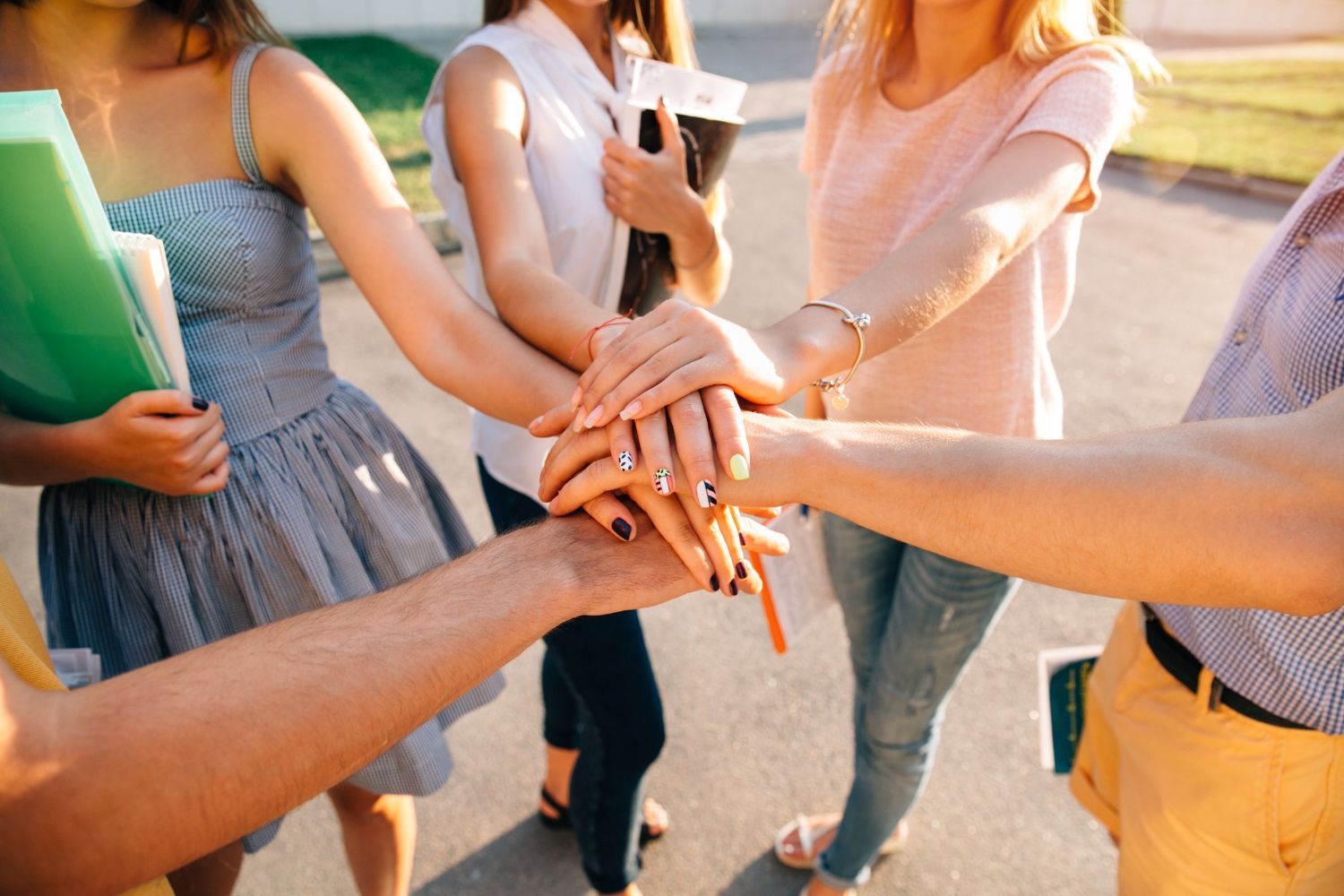 A group of people are putting their hands together in a circle.