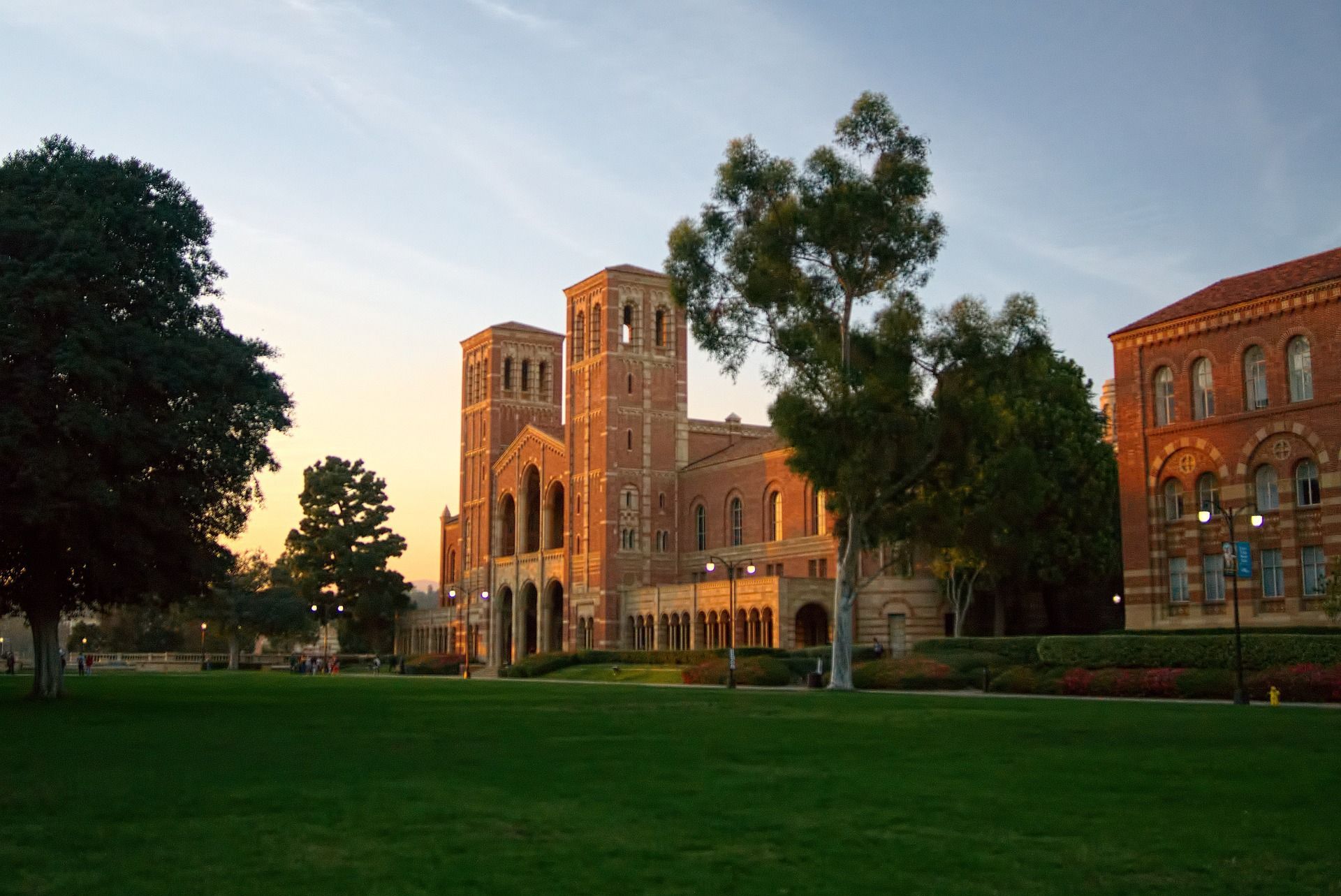 A large building with a clock tower is surrounded by trees and grass.