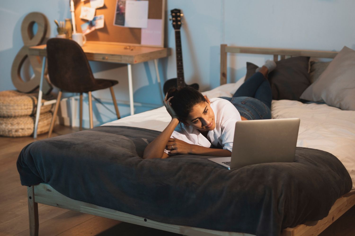 A woman is laying on a bed using a laptop computer.