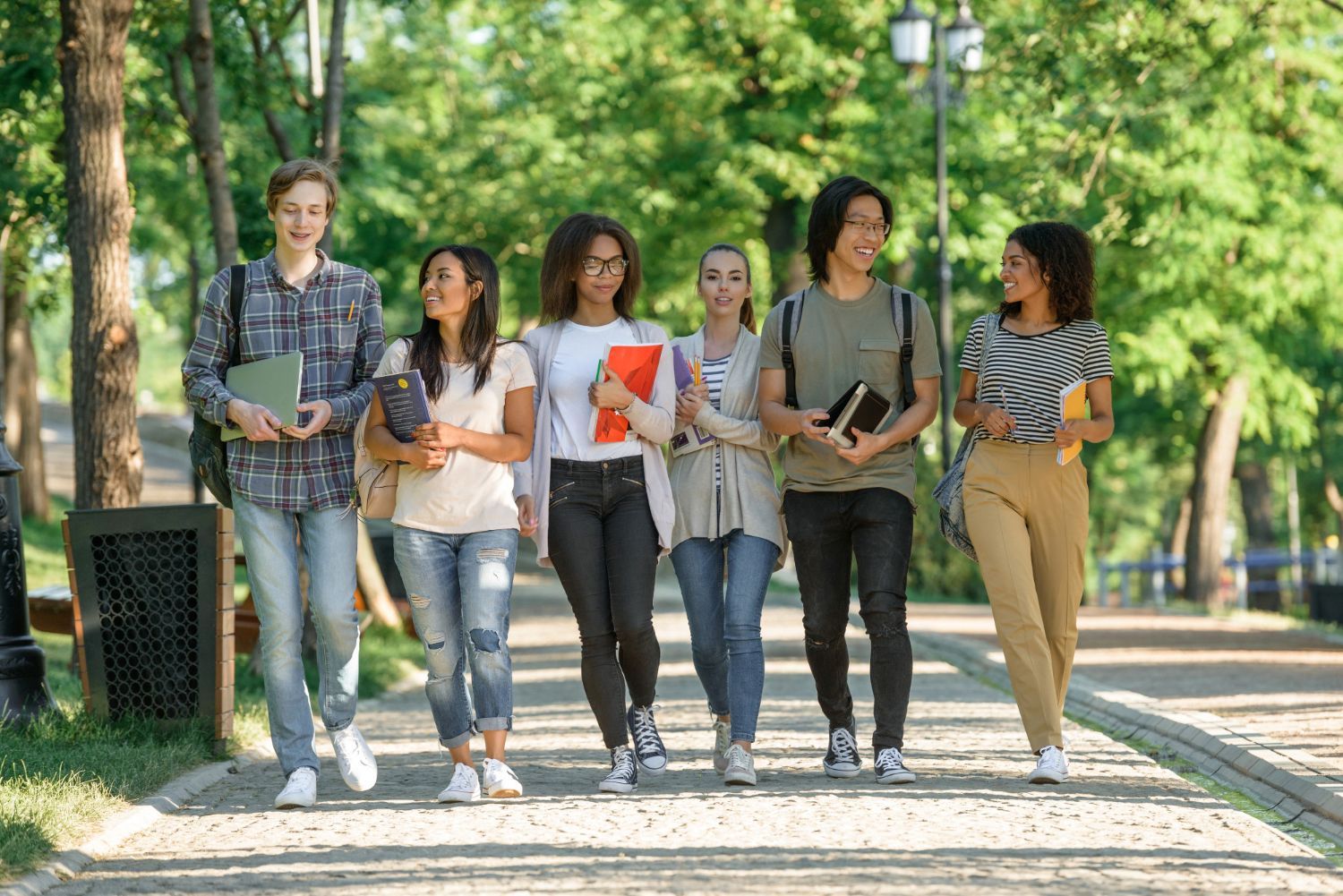 A group of students are walking down a sidewalk in a park.