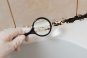 A person is holding a magnifying glass over a bathroom sink.