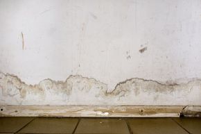 A white wall with peeling paint and a tiled floor.