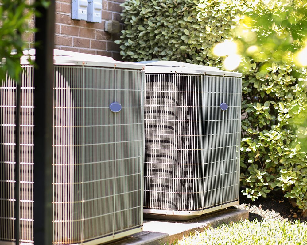 Two air conditioners are sitting outside of a brick building.