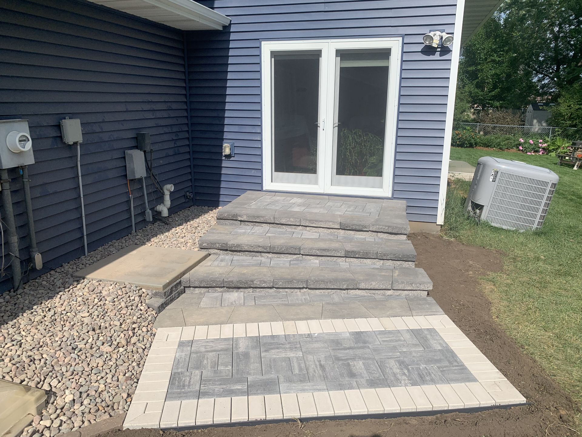 Newly installed paver patio with custom steps in a landscaped backyard in West Salem, WI