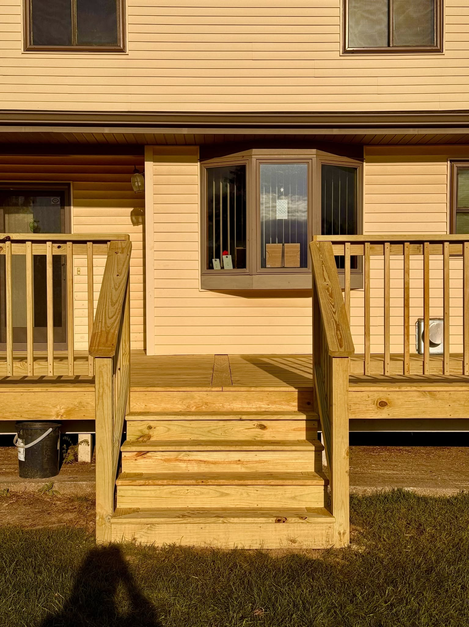 Person staining a wooden deck, showing contrast between stained and unstained boards.