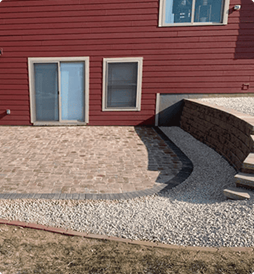A red house with a patio and stairs in front of it.