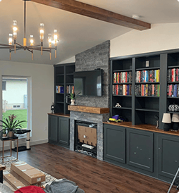 A living room with a fireplace, bookshelves, and a flat screen TV.