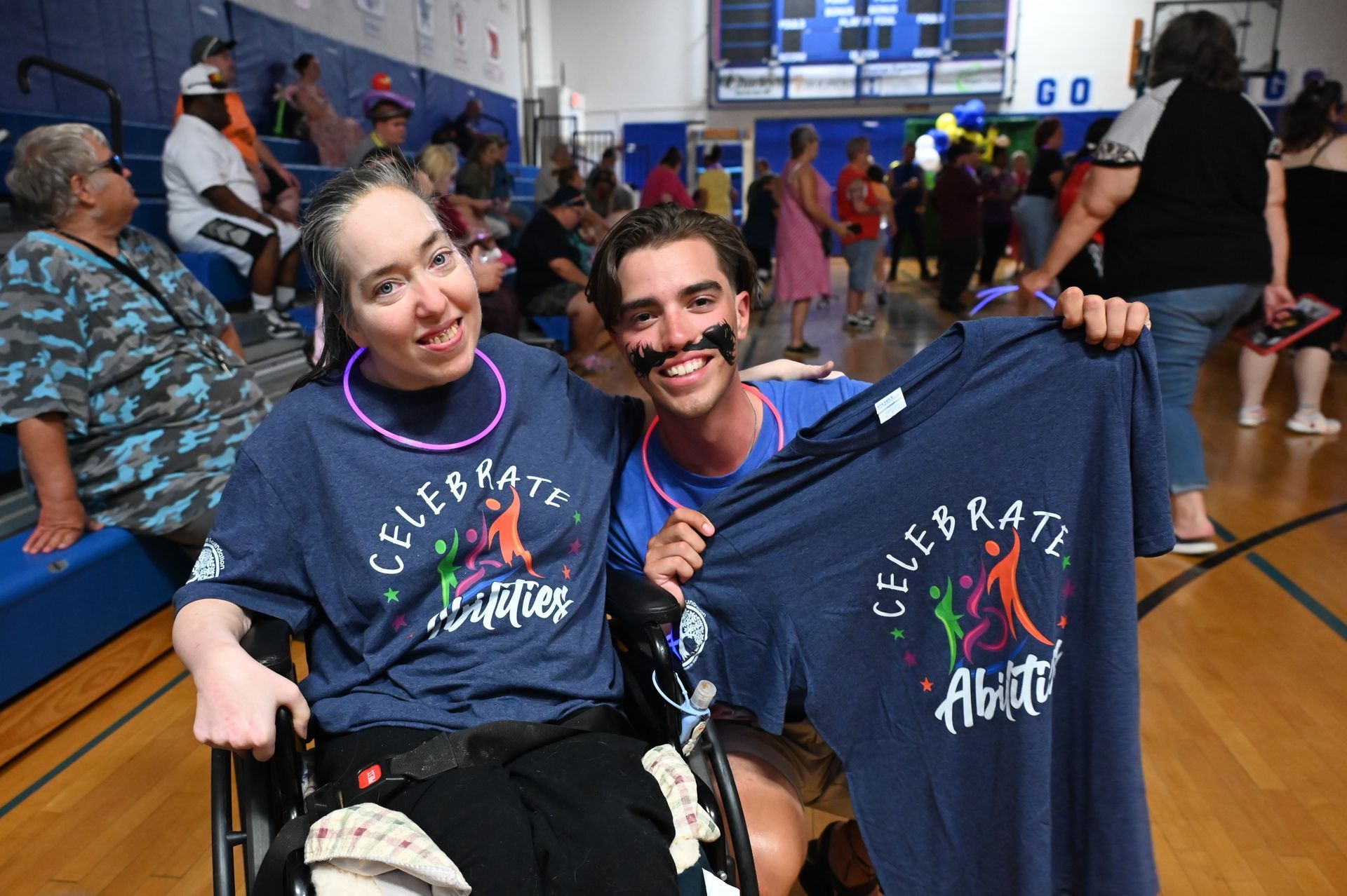 a man and a woman in a wheelchair are holding shirts that say celebrate
