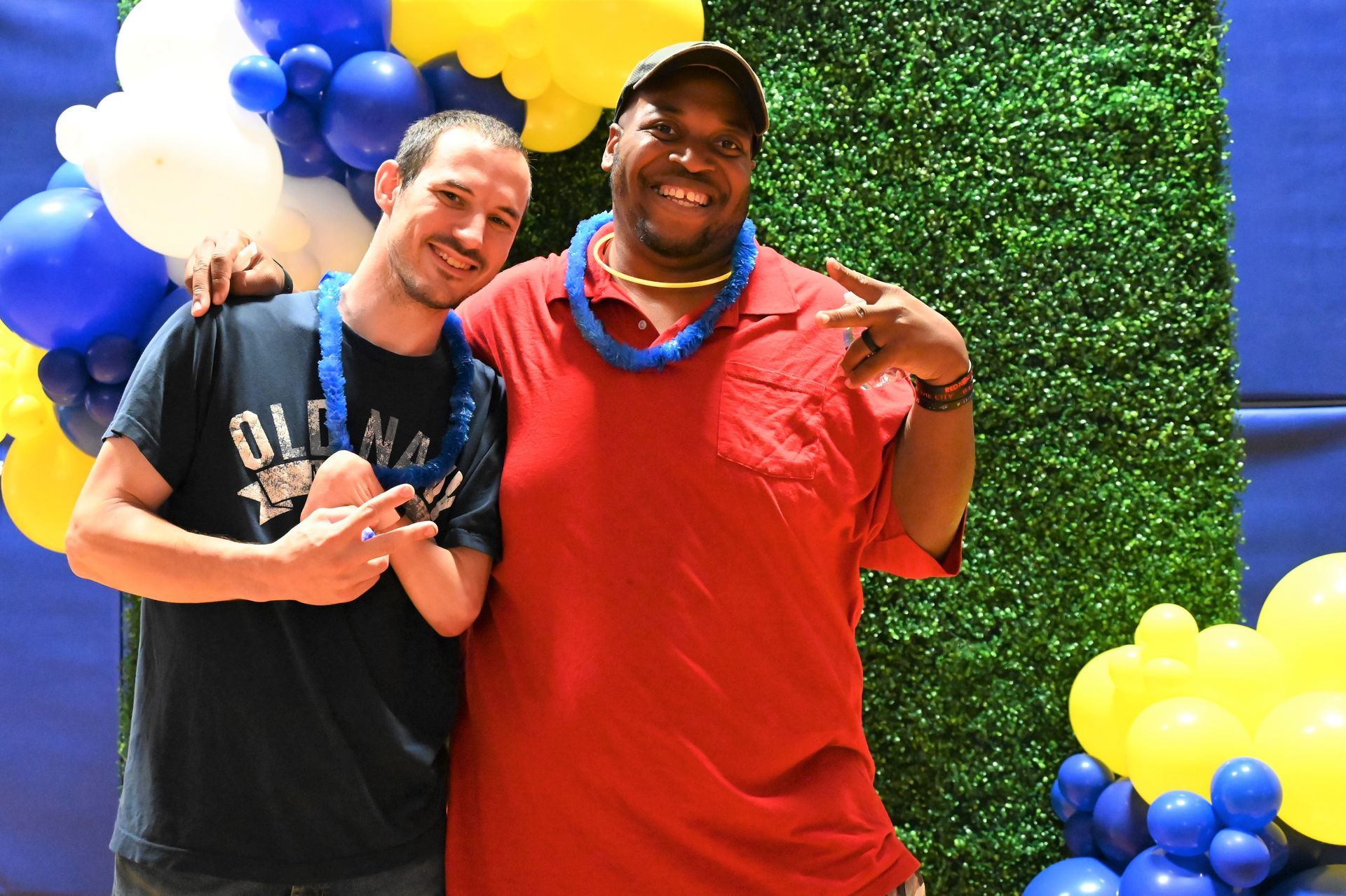 two men are posing for a picture in front of balloons .