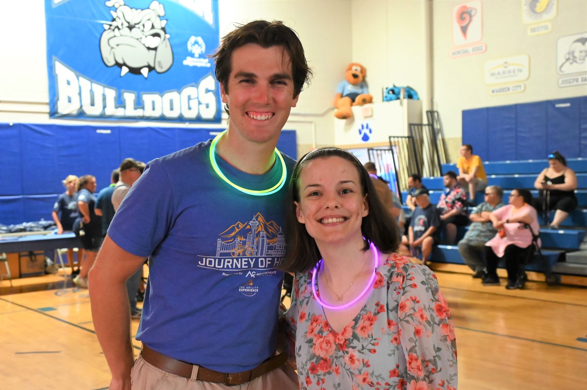 a man and a woman are posing for a picture in front of a sign that says bulldogs