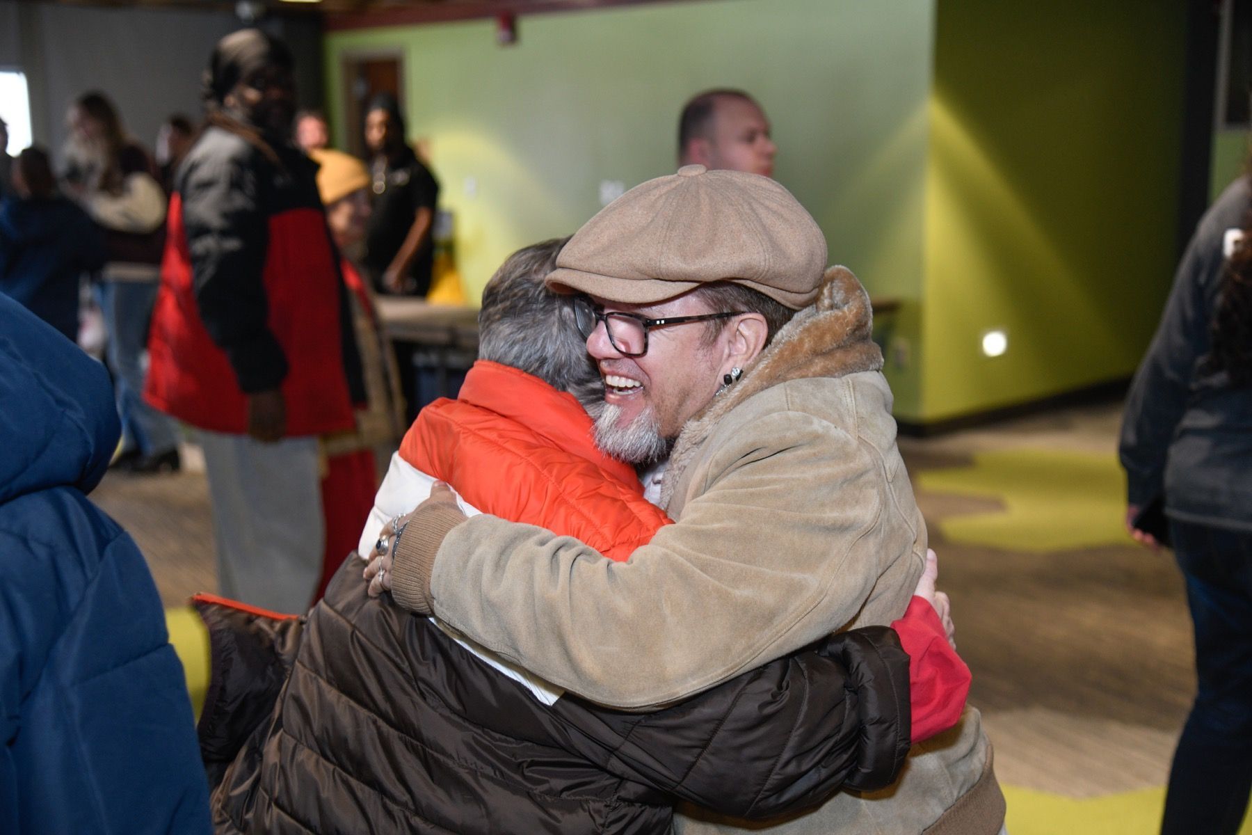 three women are standing on a baseball field holding jerseys .