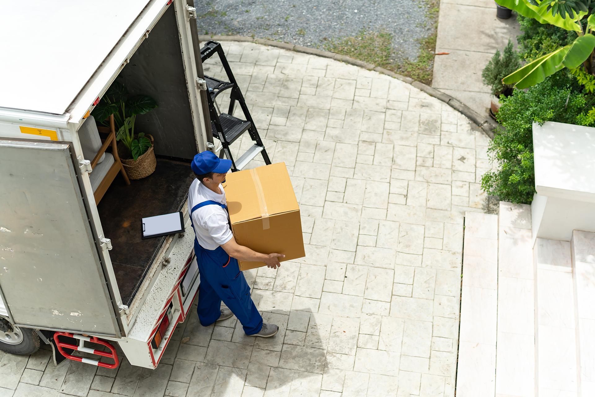 a delivery man is carrying a box out of a truck .