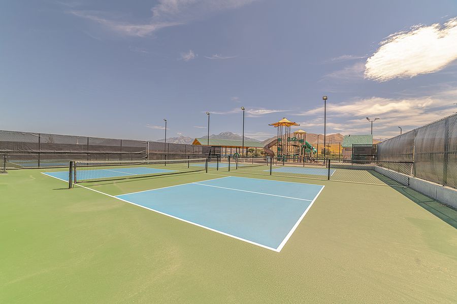 A tennis court with a playground in the background